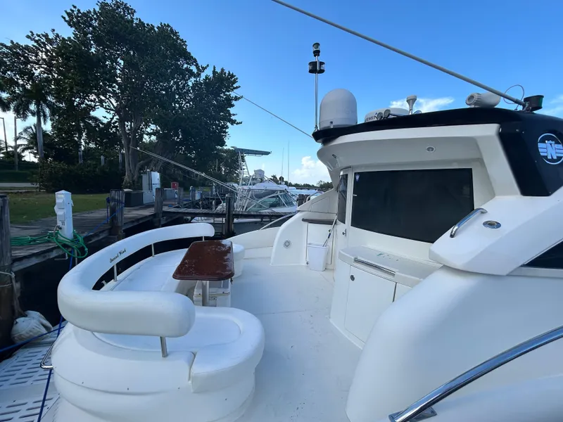 Slide: The Image of 2006 Neptunus 55 Cabrio yacht with spacious deck and seating area, docked by lush greenery. - 28