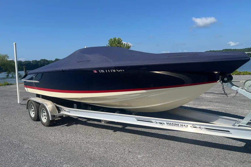 Slide: The Image of 2018 Chris-Craft Launch 23 boat on trailer, covered, parked near a lake. - 1