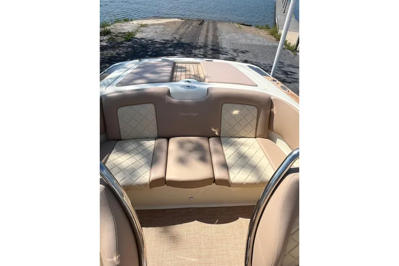 Slide: The Image of 2018 Chris-Craft Launch 23 boat interior with beige seating by the water. - 10