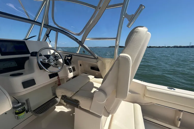 Slide: The Image of 2021 Grady-White Gulfstream 232 boat interior with steering wheel and seating, on open water. - 28