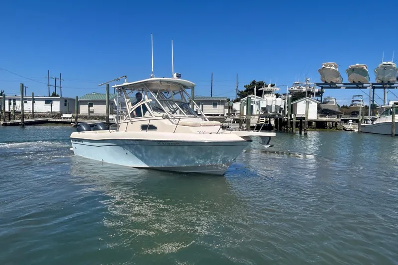 Slide: The Image of 2021 Grady-White Gulfstream 232 boat navigating a marina under clear blue skies. - 6