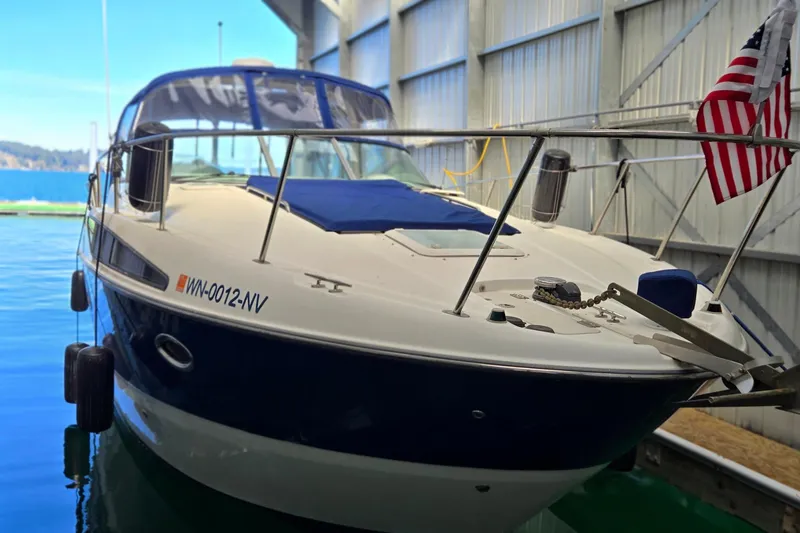 The Image of 2007 Bayliner 325 boat docked indoors with American flag displayed. - 0