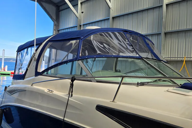 Slide: The Image of 2007 Bayliner 325 boat with blue canopy docked in a marina. - 2