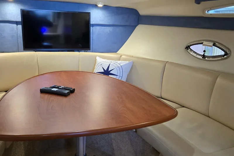 Slide: The Image of Interior of 2007 Bayliner 325 yacht with TV, table, and beige seating. - 23