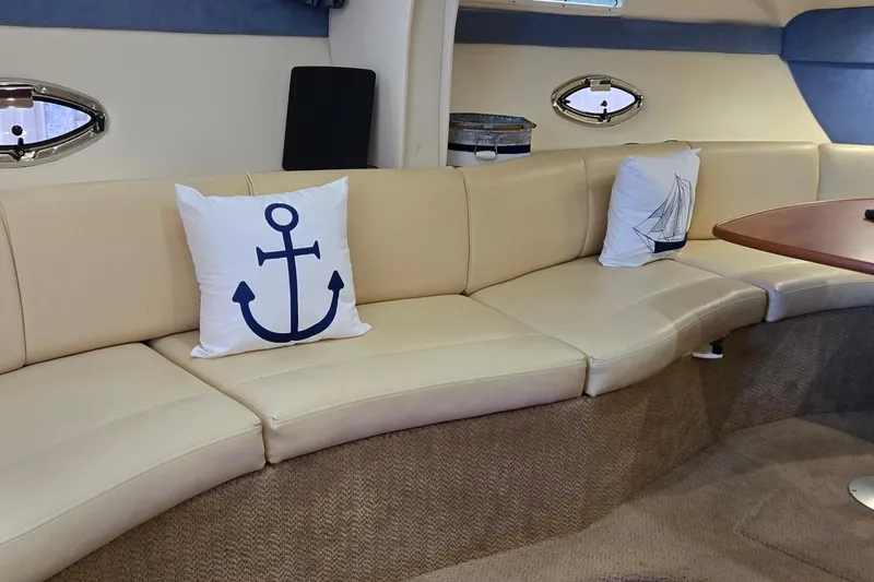 Slide: The Image of Interior of a 2007 Bayliner 325 boat with beige seating and nautical-themed pillows. - 24