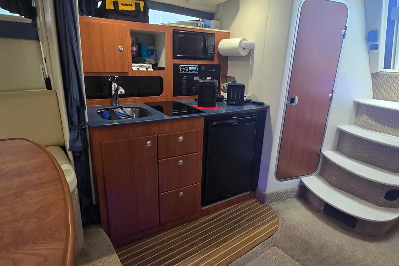 Slide: The Image of 2007 Bayliner 325 yacht interior with kitchenette, featuring sink, microwave, and compact fridge. - 27