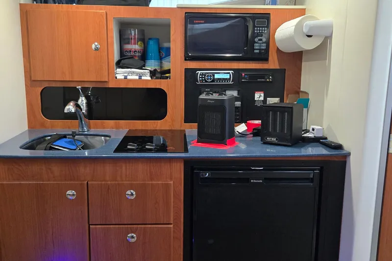 Slide: The Image of Compact kitchen area in a 2007 Bayliner 325 boat with appliances and storage. - 29