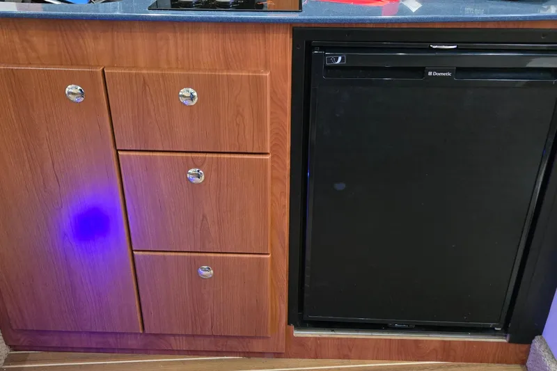 Slide: The Image of 2007 Bayliner 325 interior with wooden cabinetry and Dometic refrigerator. - 31