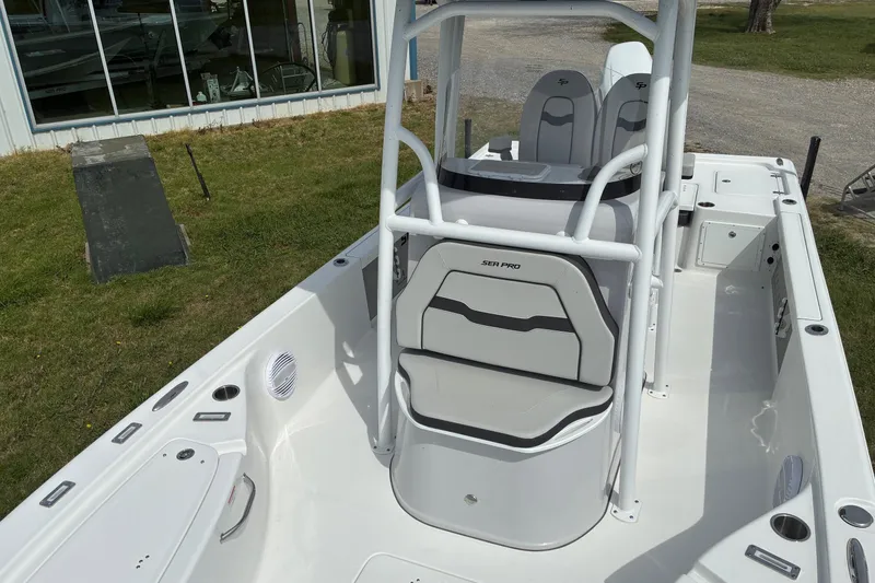 Slide: The Image of 2026 Sea Pro 250 Bay boat interior with seating and console, parked outdoors. - 6
