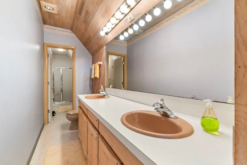 Slide: The Image of Vintage 1976 boathouse bathroom with dual sinks, large mirror, and wooden accents. - 18