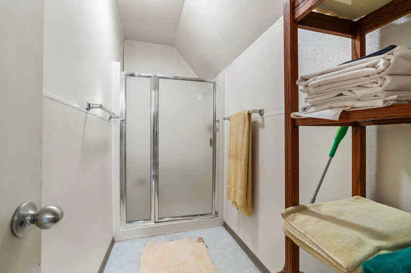 Slide: The Image of Small bathroom with shower, wooden shelving, and towels in a 1976 Custom Boathouse. - 19