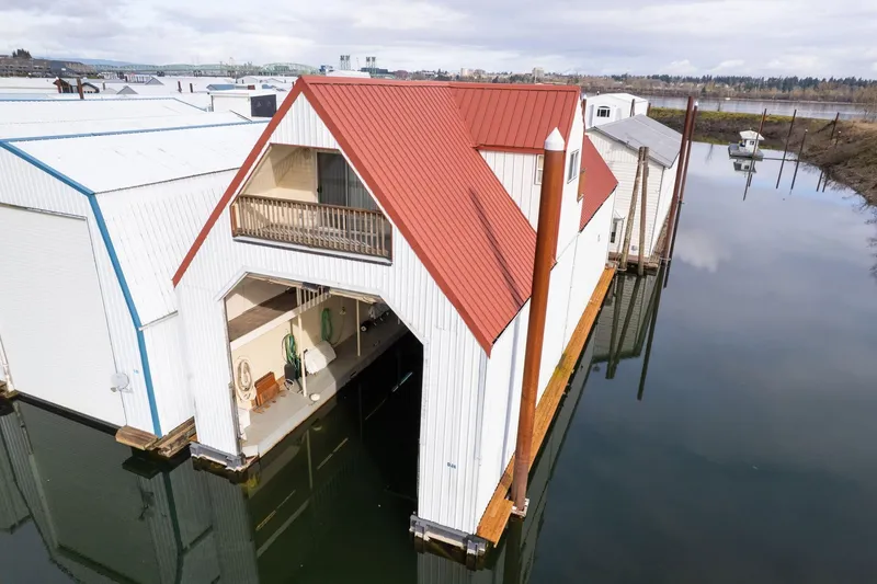 Slide: The Image of Custom 1976 boathouse with red roof, docked on calm water, featuring open garage. - 2