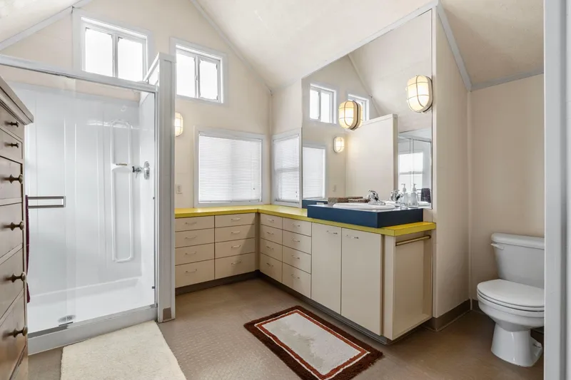 Slide: The Image of Spacious 1976 custom boathouse bathroom with shower, vanity, and toilet, featuring ample natural light. - 33