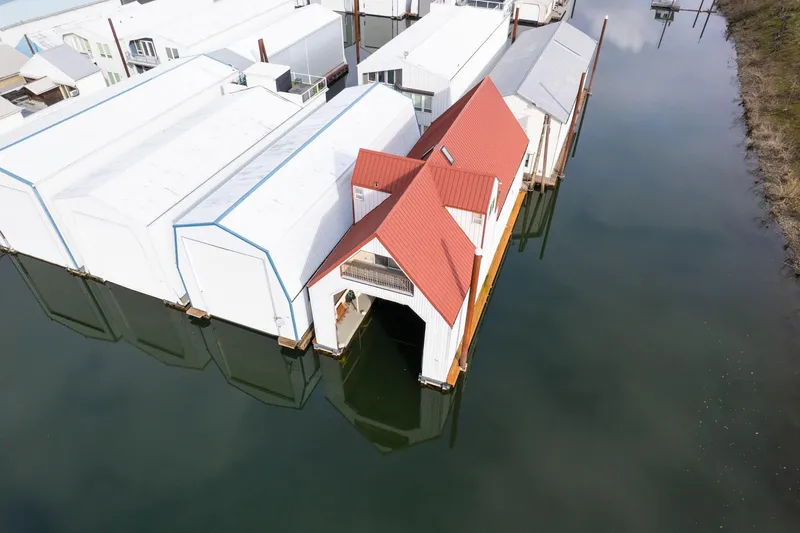 Slide: The Image of Aerial view of a 1976 custom boathouse with a red roof on calm water. - 43