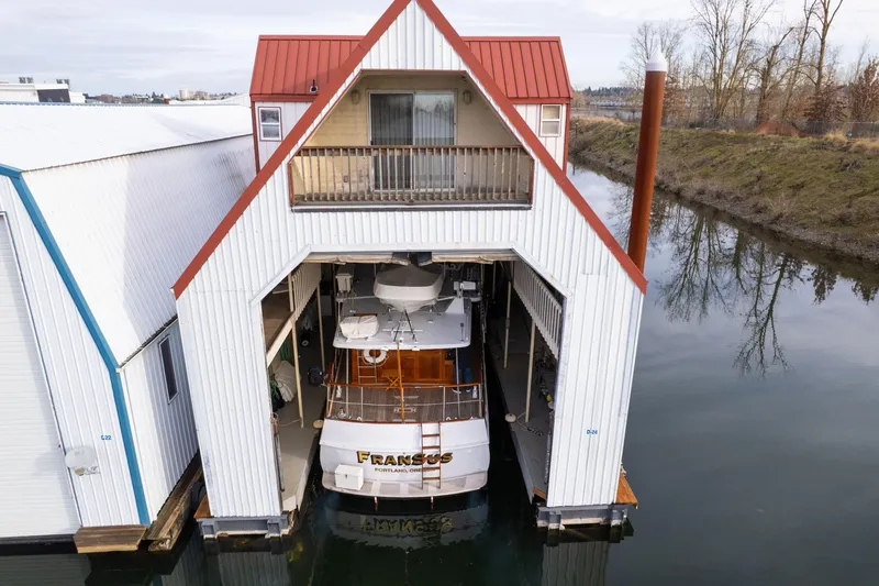 Slide: The Image of Custom 1976 boathouse with docked boat, featuring red roof and balcony, on calm water. - 44