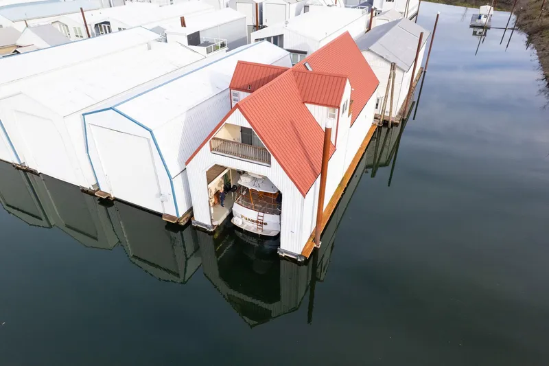 Slide: The Image of Aerial view of a 1976 custom boathouse with red roof on calm water. - 45