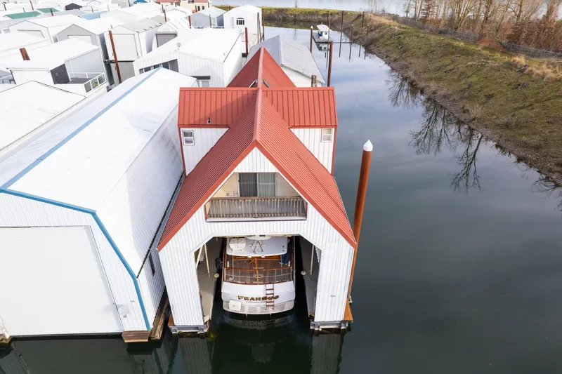 Slide: The Image of Aerial view of a 1976 custom boathouse with red roof, housing a boat on calm water. - 46
