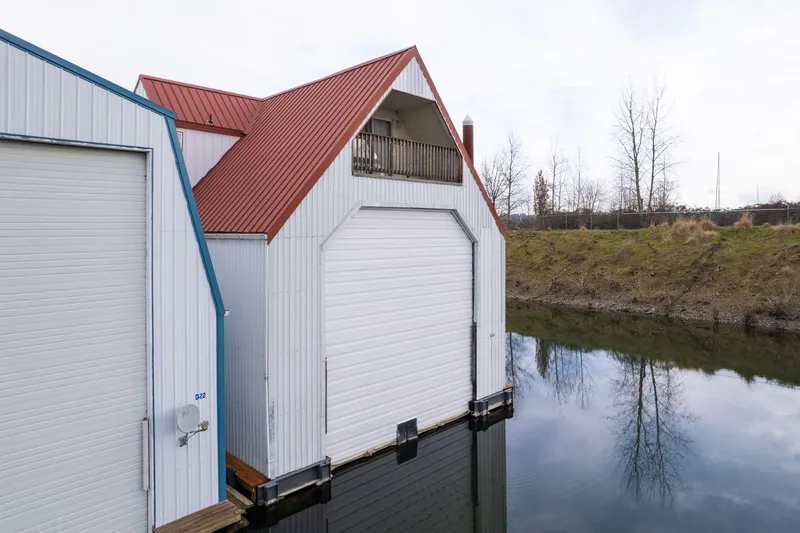 Slide: The Image of Custom 1976 boathouse with red roof, white siding, and water reflection. - 47