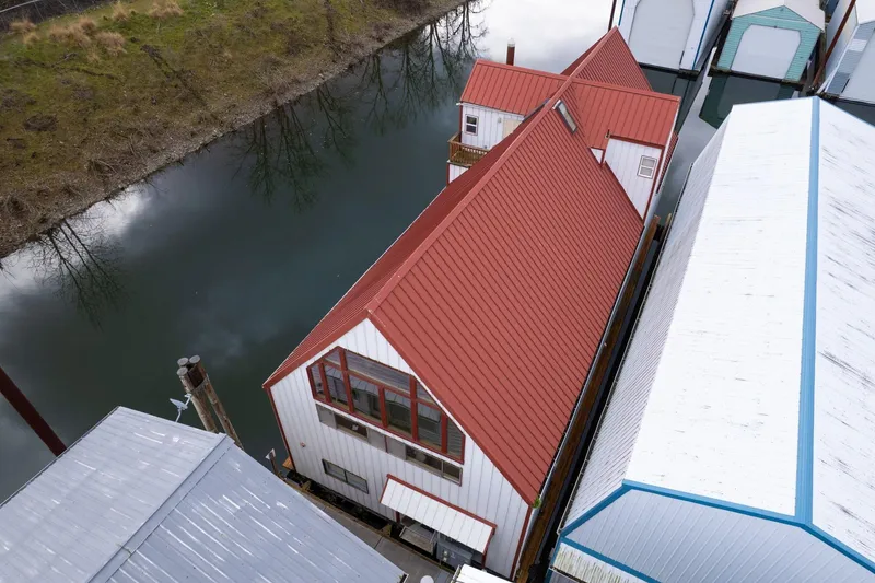 Slide: The Image of Aerial view of a 1976 custom boathouse with red roof by a calm river. - 49