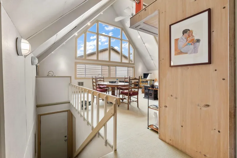 Slide: The Image of A-frame boathouse interior with large windows, wooden accents, and cozy dining area, built in 1976. - 6