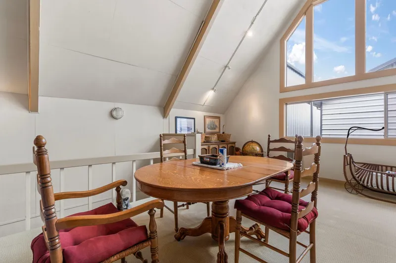 Slide: The Image of Cozy boathouse interior with wooden dining table, chairs, and large windows, built in 1976. - 8