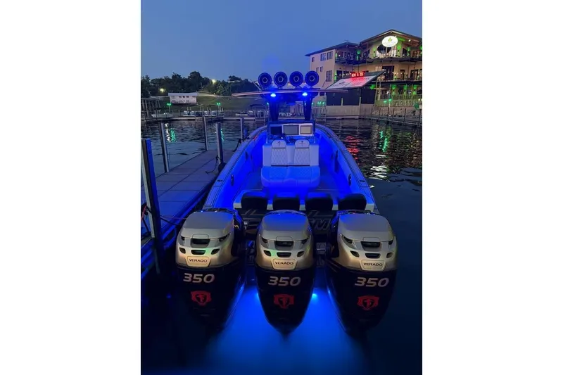 Slide: The Image of 2017 Statement 380 Open boat with triple Verado 350 engines, illuminated by blue lights at dock. - 76
