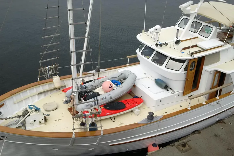 Slide: The Image of 1971 Philbrooks Trawler with dinghy and kayak on deck, docked by calm waters. - 16