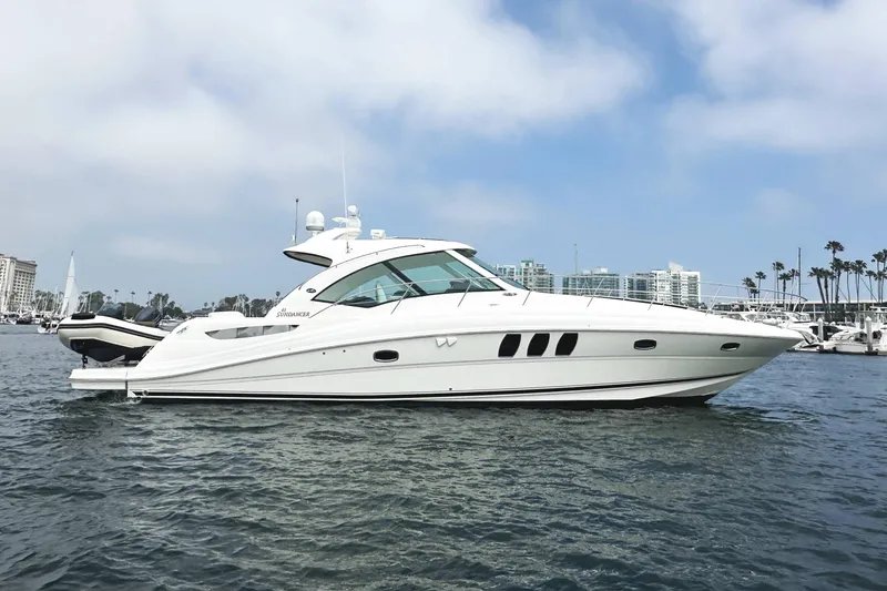 The Image of 2006 Sea Ray 48 Sundancer yacht on water, with cityscape and palm trees in background. - 0