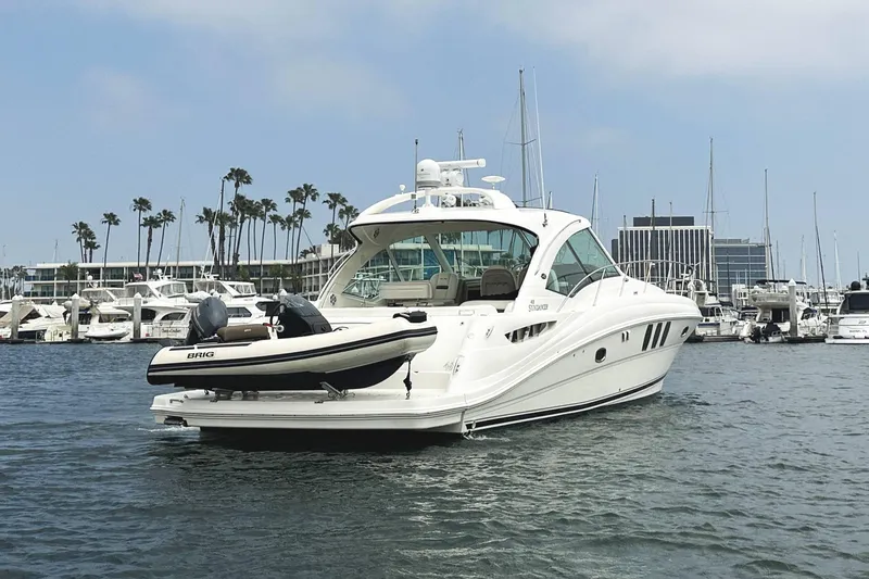 Slide: The Image of 2006 Sea Ray 48 Sundancer yacht docked in marina with palm trees and buildings. - 2