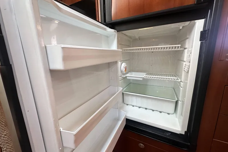 Slide: The Image of Open refrigerator inside 2006 Sea Ray 48 Sundancer yacht, showing empty shelves and compartments. - 20