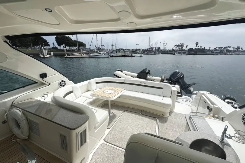 Slide: The Image of 2006 Sea Ray 48 Sundancer yacht interior with seating area, table, and marina view. - 6