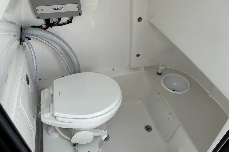 Slide: The Image of Compact bathroom in 2026 Sea Pro 245FLX Sandbar boat, featuring toilet and sink. - 19