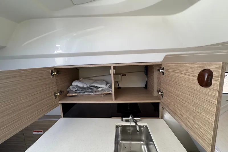 Slide: The Image of 2026 Jeanneau Leader 9.0 WA Series 2 interior with open wooden cabinets and sink. - 13
