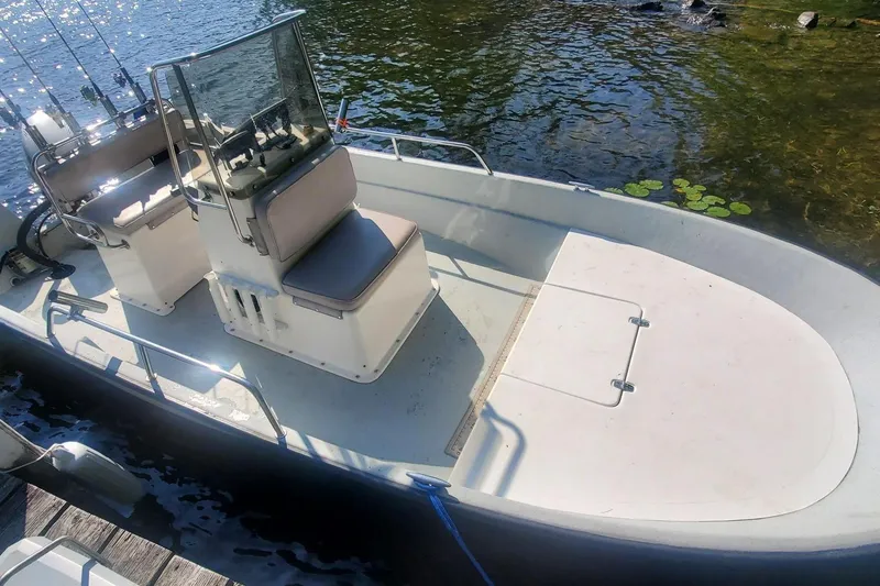 Slide: The Image of 1999 Maritime Skiff 1690 boat docked on calm water with fishing rods. - 2