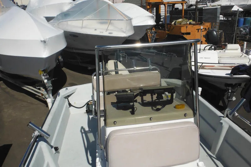 Slide: The Image of 1999 Maritime Skiff 1690 boat in storage yard, surrounded by covered vessels. - 30