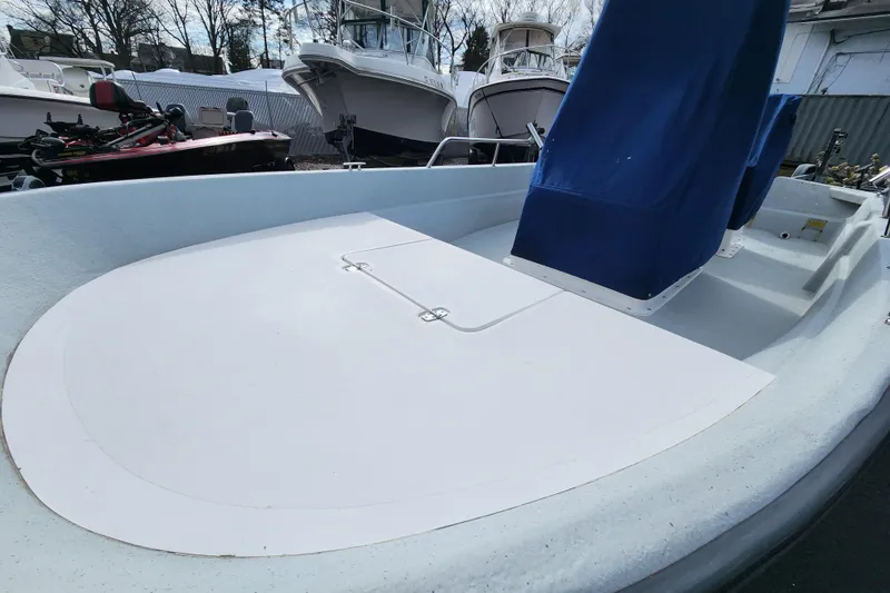 Slide: The Image of 1999 Maritime Skiff 1690 boat interior with blue covers, docked among other vessels. - 5