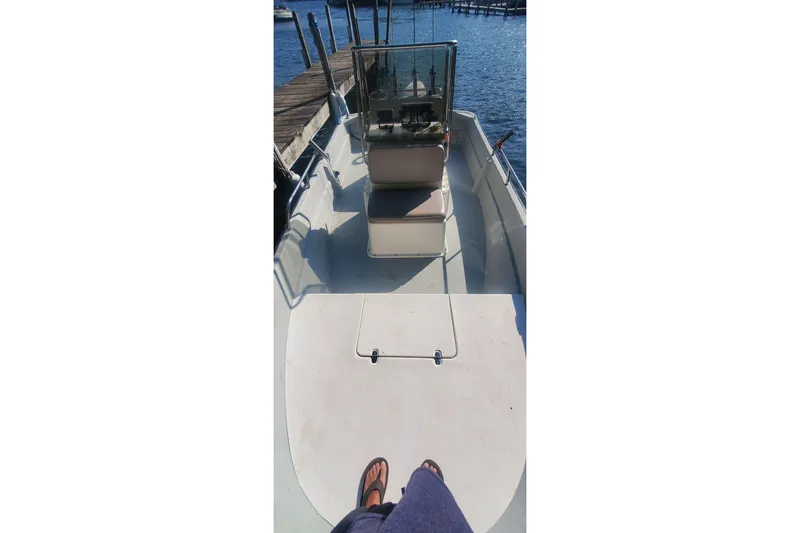 Slide: The Image of 1999 Maritime Skiff 1690 boat docked, featuring console and seating, with water view. - 6