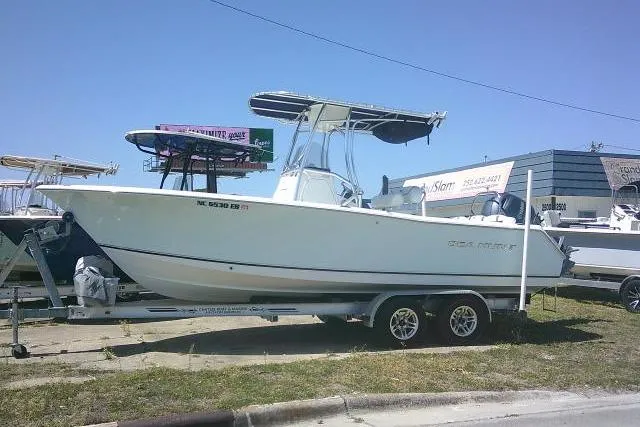 The Image of 2015 Sea Hunt Ultra 225 boat on trailer, parked outdoors under clear sky. - 1