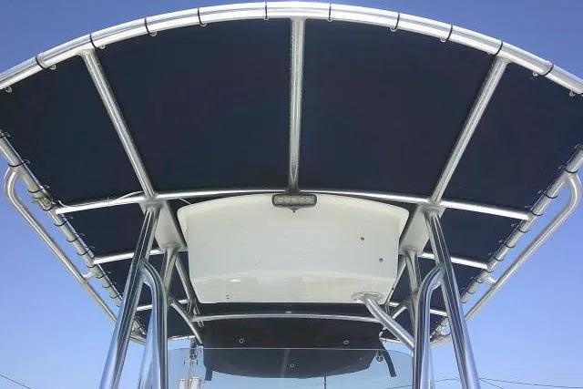 Slide: The Image of 2015 Sea Hunt Ultra 225 boat T-top with blue canvas under clear sky. - 17