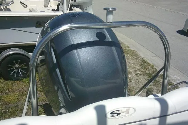 Slide: The Image of 2015 Sea Hunt Ultra 225 boat engine with stainless steel railing, parked on grass. - 28
