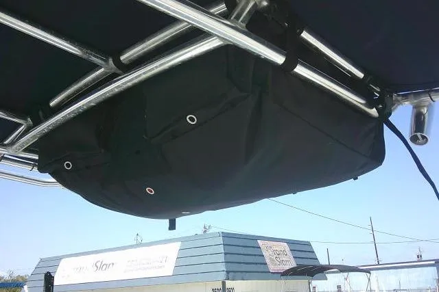 Slide: The Image of 2015 Sea Hunt Ultra 225 T-top storage bag under metal frame, outdoor setting. - 48