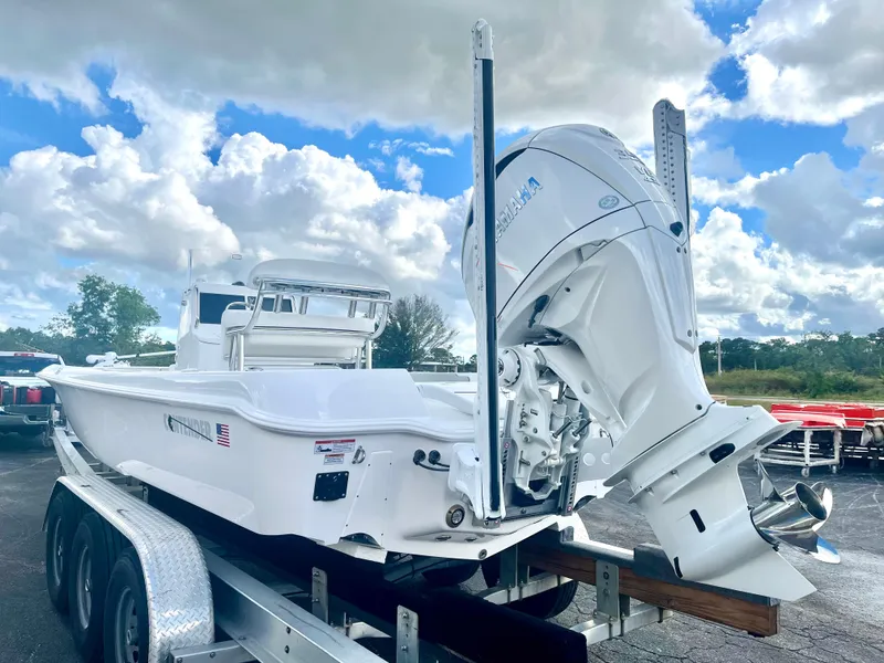 Slide: The Image of 2025 Contender 26 Bay boat on trailer, featuring powerful outboard motor under cloudy sky. - 4