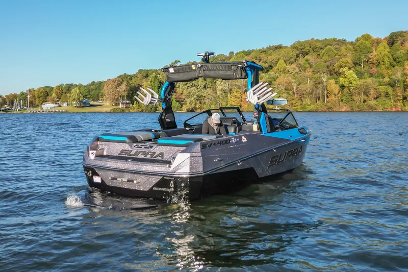 Slide: The Image of 2024 Supra SV 400 boat cruising on a scenic lake with lush green shoreline. - 11