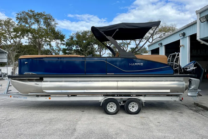 The Image of 2026 Harris Sunliner 250 pontoon boat on trailer, blue sky. - 1