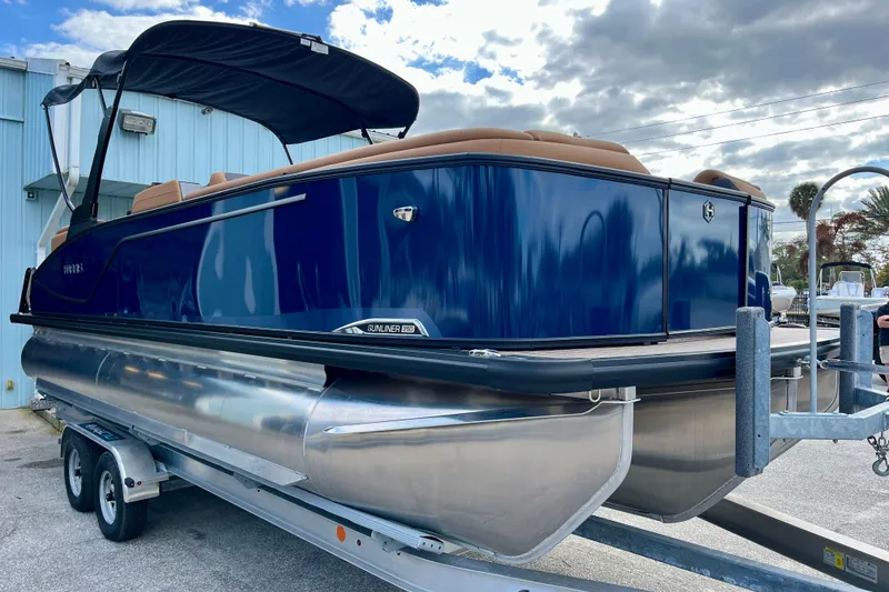 Slide: The Image of 2026 Harris Sunliner 250 pontoon boat on trailer, blue hull, black canopy. - 4