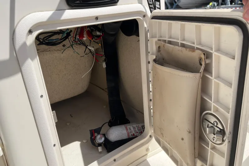 Slide: The Image of Open storage compartment in a 2015 Carolina Skiff JV15CC boat, showing wiring and a fire extinguisher. - 15