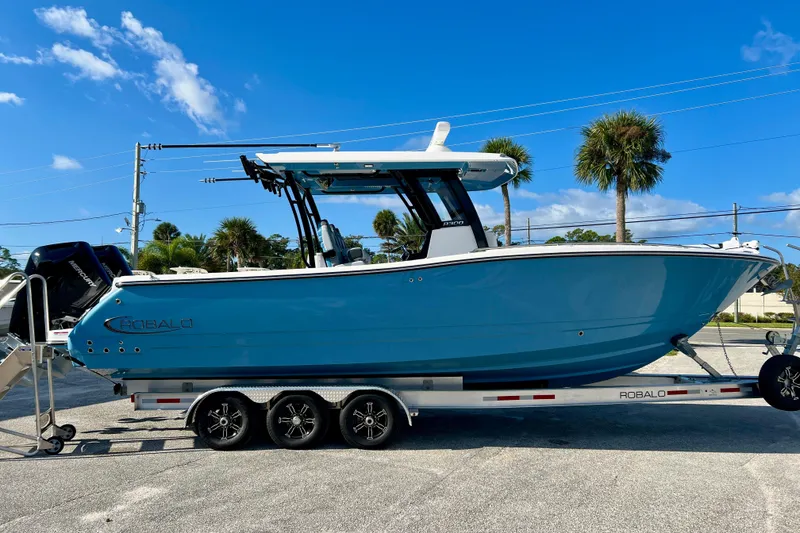The Image of 2026 Robalo R300 Center Console boat on trailer under clear blue sky. - 1