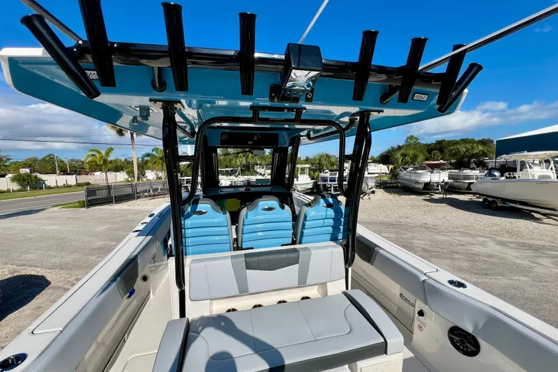Slide: The Image of 2026 Robalo R300 Center Console boat with blue seating and rod holders, parked outdoors. - 19