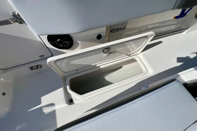 Slide: The Image of 2026 Robalo R300 Center Console boat storage compartment with open hatch and speaker. - 22