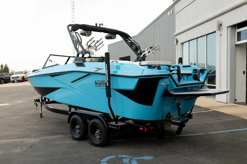 Slide: The Image of 2023 Heyday H22 boat in vibrant blue on a trailer outside a modern building. - 4